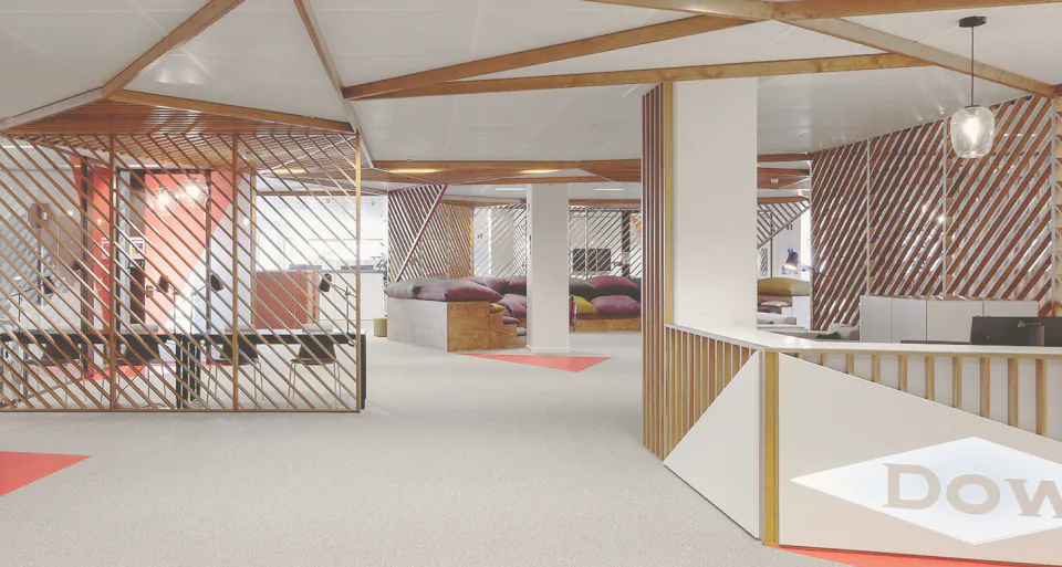 The central arena: diagonal timber slat screens, cushioned tiered seating and red floor graphics