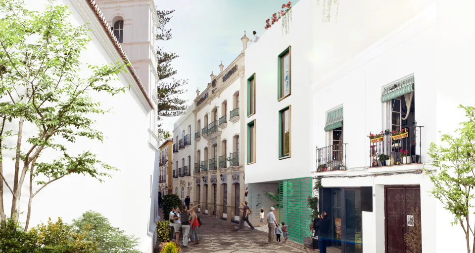 Street view of the library’s white façade with green window frames among the houses of Nerja’s old town
